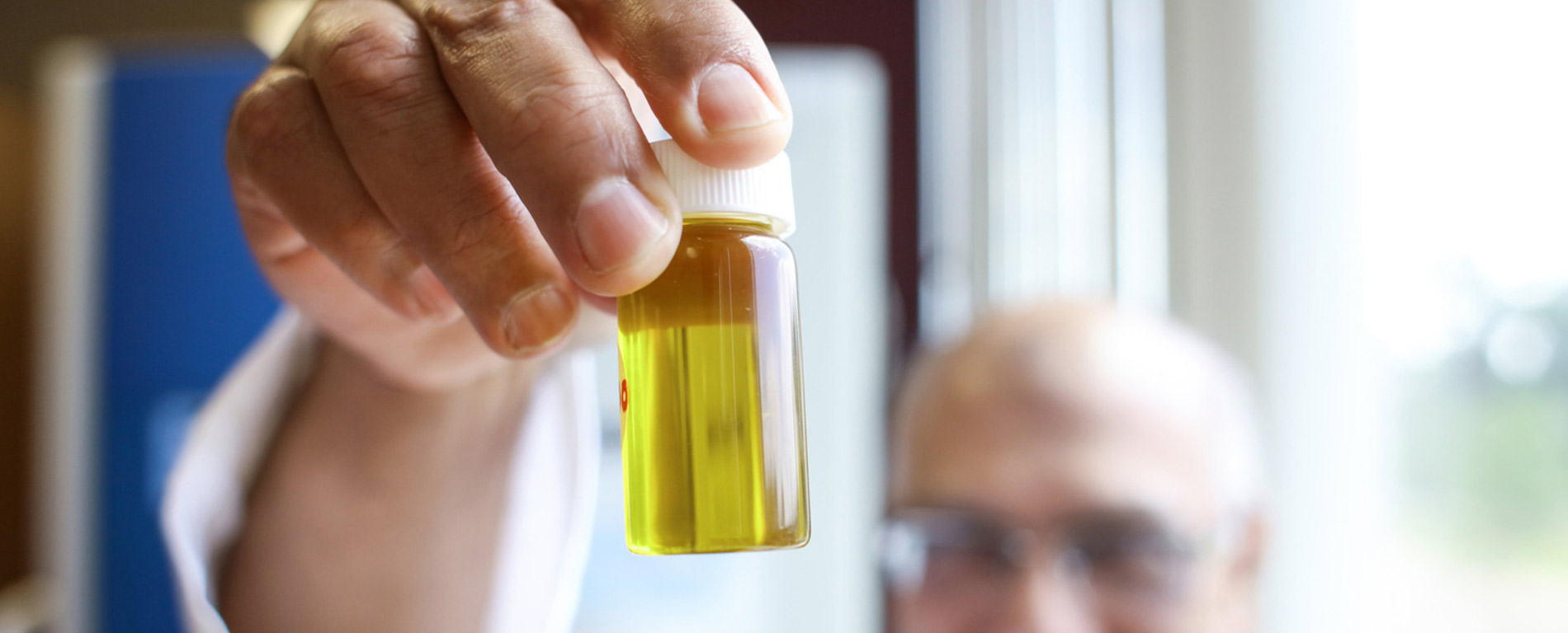 professor holding a pharmaceutical container with fluid in it
