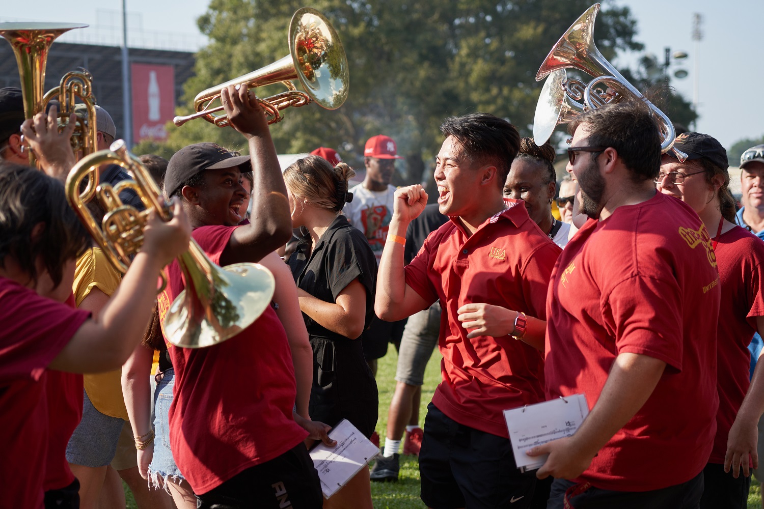 Sound of Today A group of students wearing maroon t-shirts cheer and hold instruments.