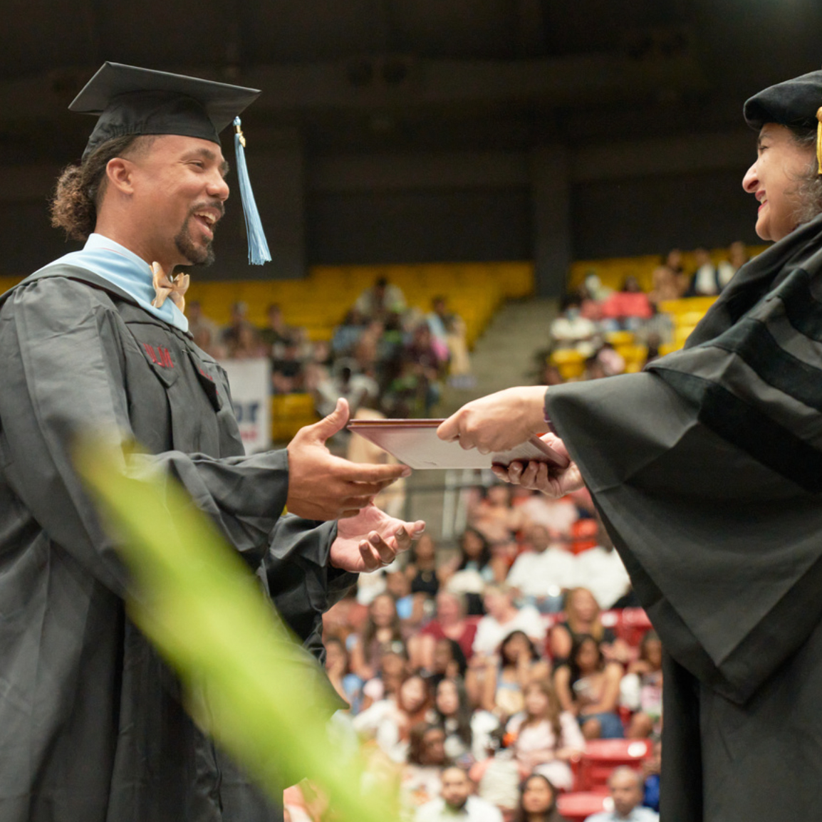 Graduate student receiving degree from dean, both are smiling
