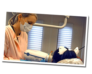 student taking x-rays using a handheld x-ray device on a patient in dental clinic
