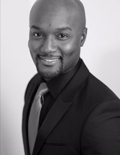 Composer Sydney Guillaume is standing and wearing a coat and tie.