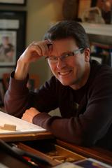 Composer Stephen Paulus is seated at a piano with one hand against his forehead.