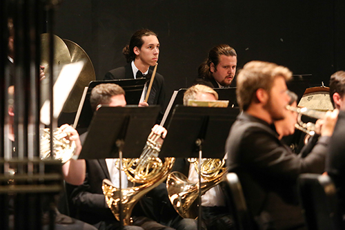 French horn players, trumpet player and percussionists performing on stage in Brown Auditiorium.