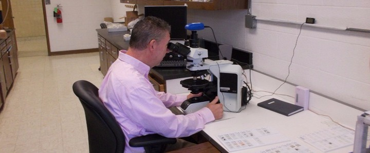 Mr. John Herrock examing samples in the absetos lab