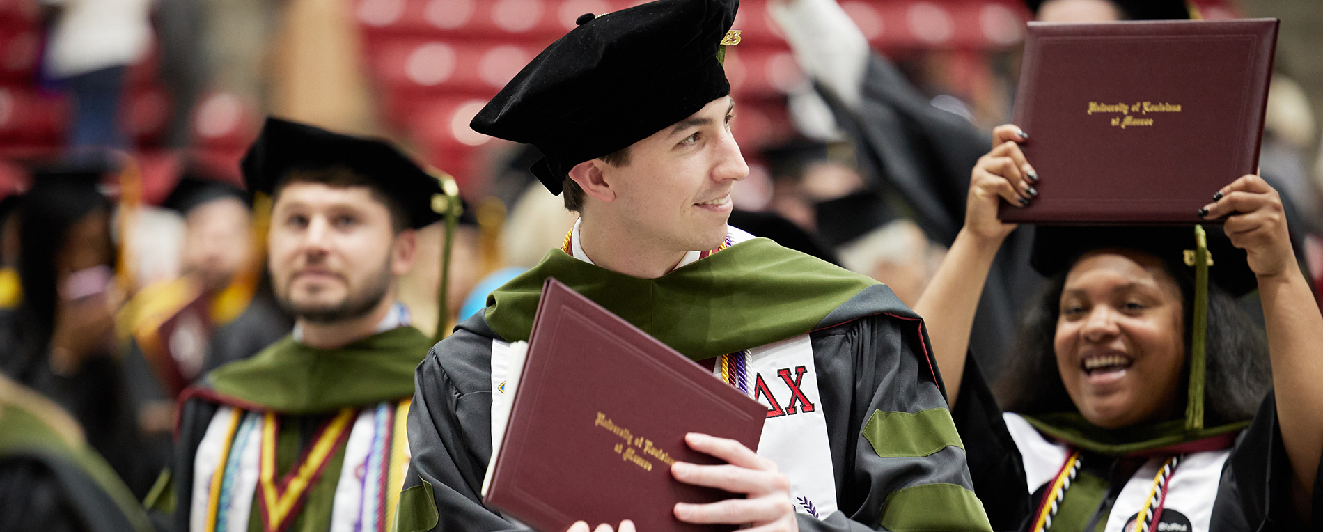 College of Pharmacy students displaying their diploma covers at graduation in Fant Ewing Coliseum.