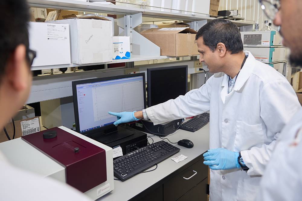 Image of graduate student explaining a piece of equipment in Dr. Matthaiolampakis' lab