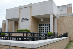 The front entrance Emy-Lou Biedenharn Recital Hall is constructed of brown brick bordered by flower beds.
